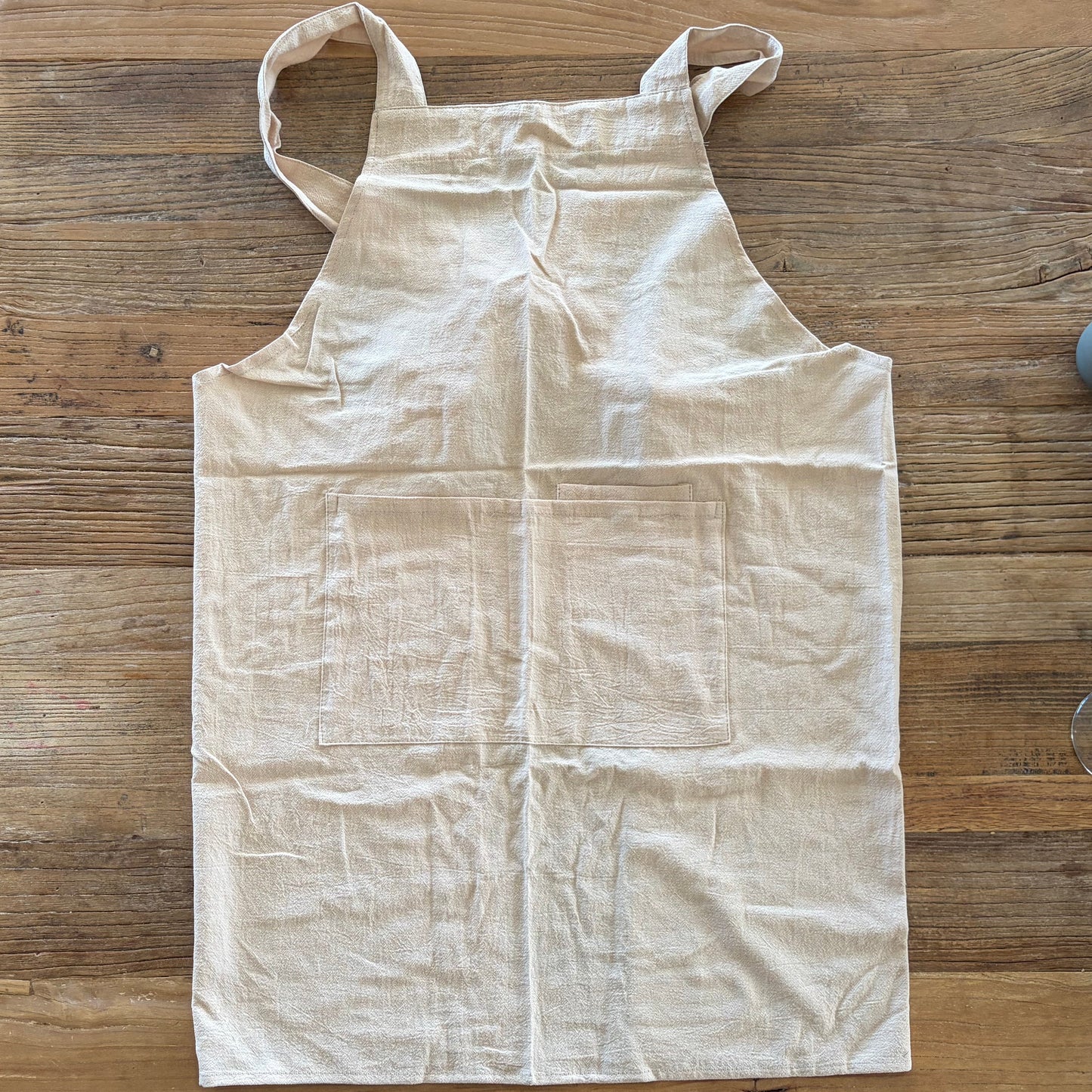 Beige Fabric apron for working with clay laid out on a wooden surface