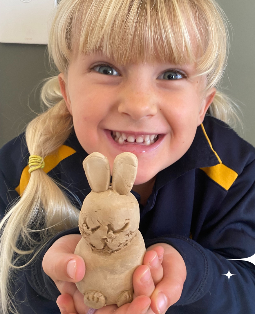A kid proudly holding a bunny she created from a Clay play airdry kit