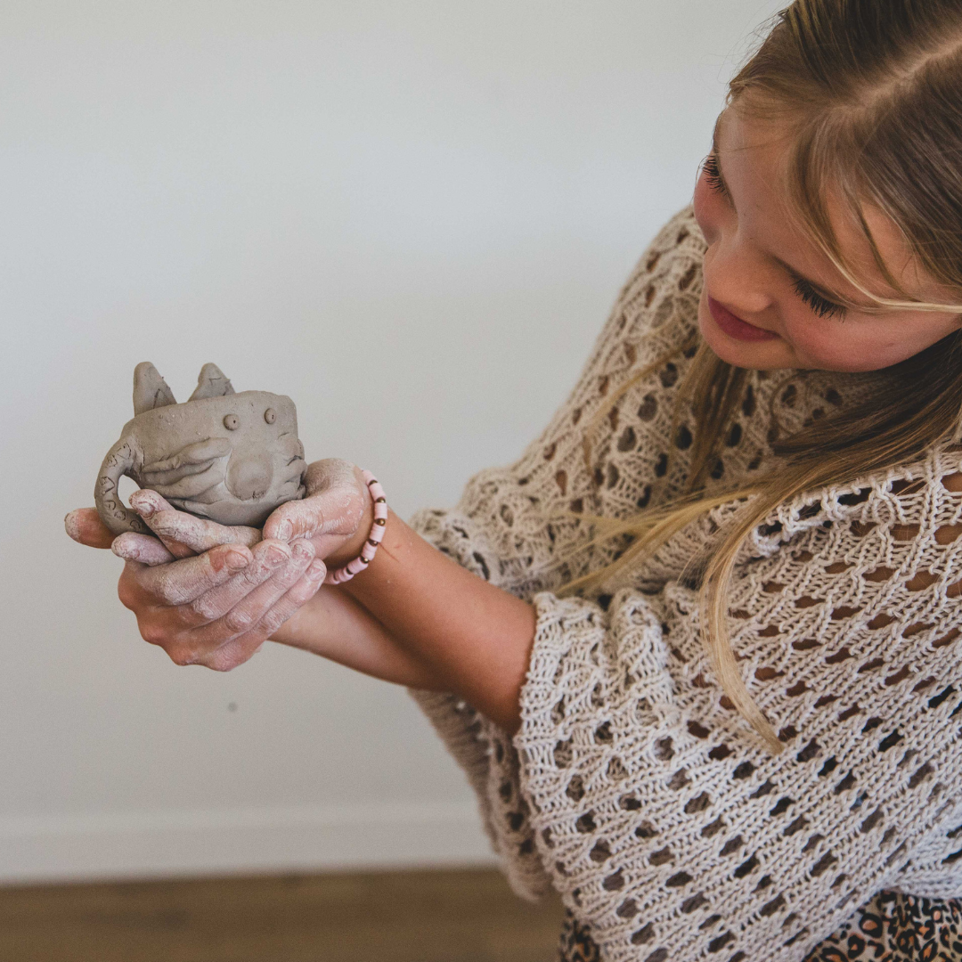 A teenage girl holding a cat face cup she created from an Clay Play airdry Kids kit
