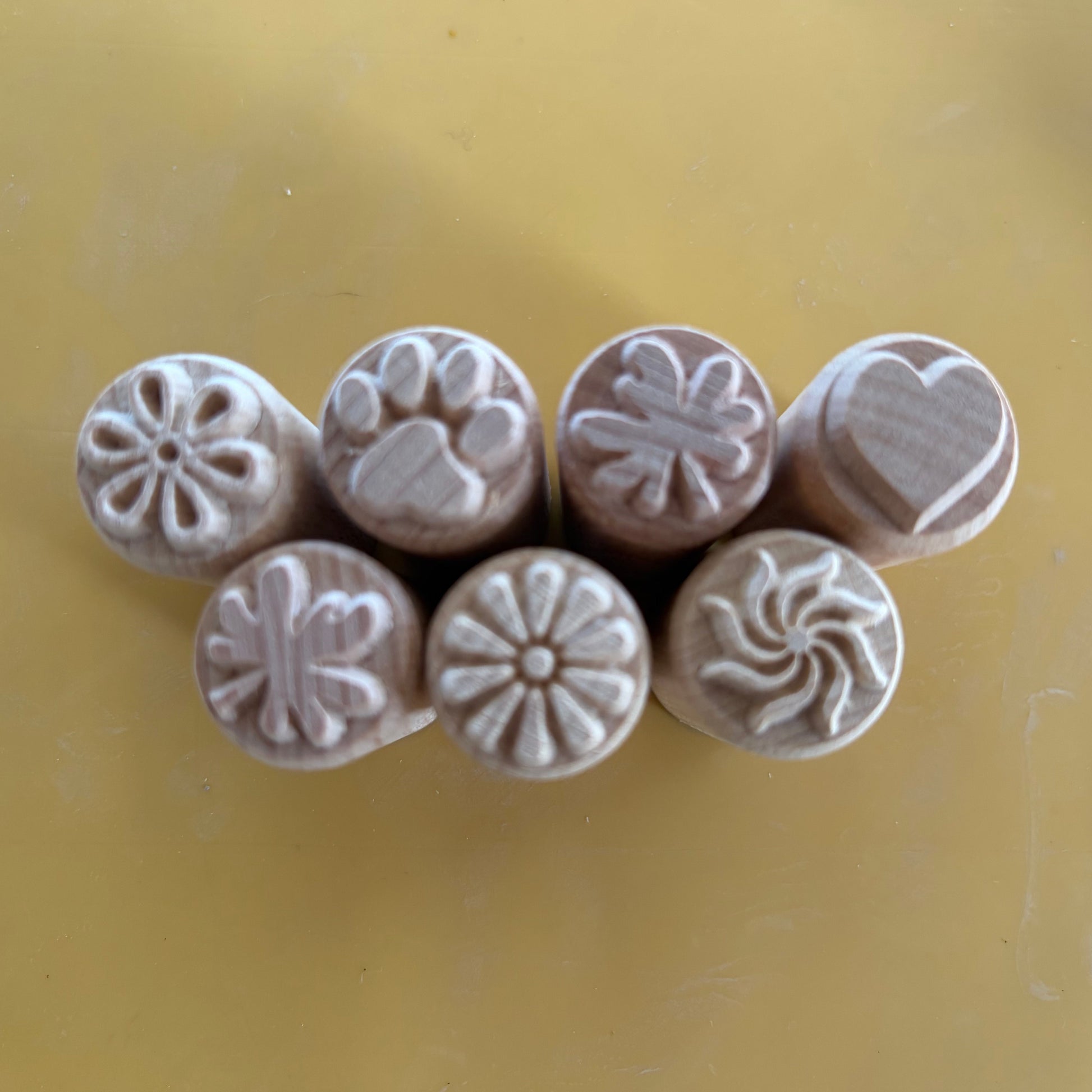 Set of seven patterned clay stamps on a yellow background