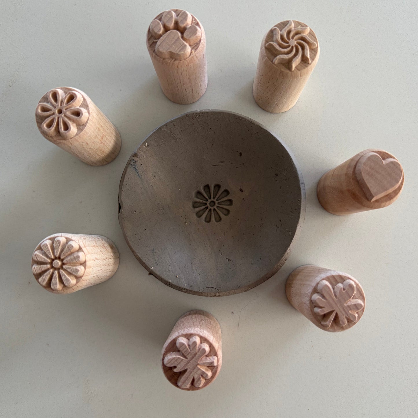 Set of wooden clay stamps with various shapes around a central round clay dish