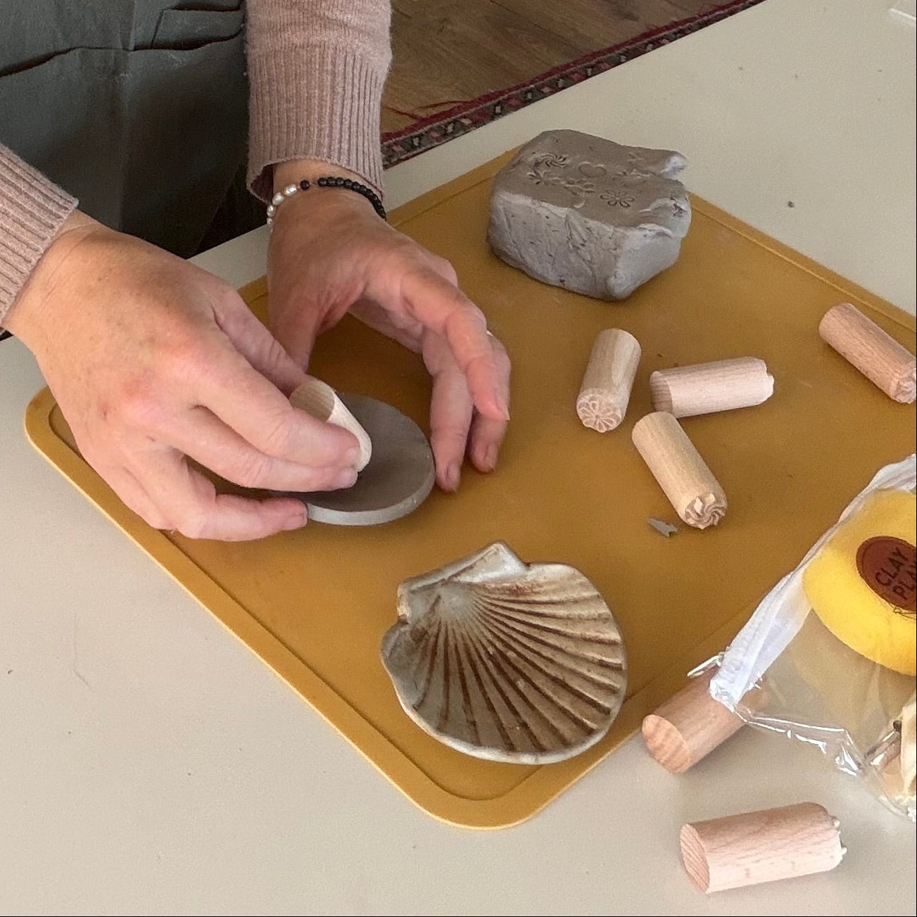 Woman in a kitchen stamping clay with a clay stamp.