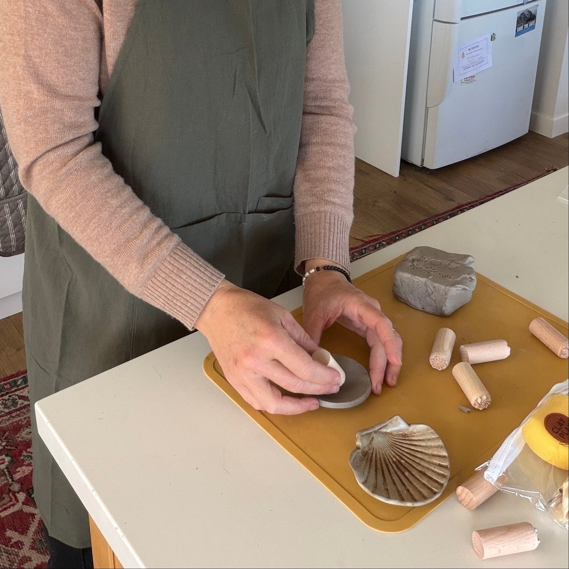 Woman in a kitchen stamping clay in handmade pottery.